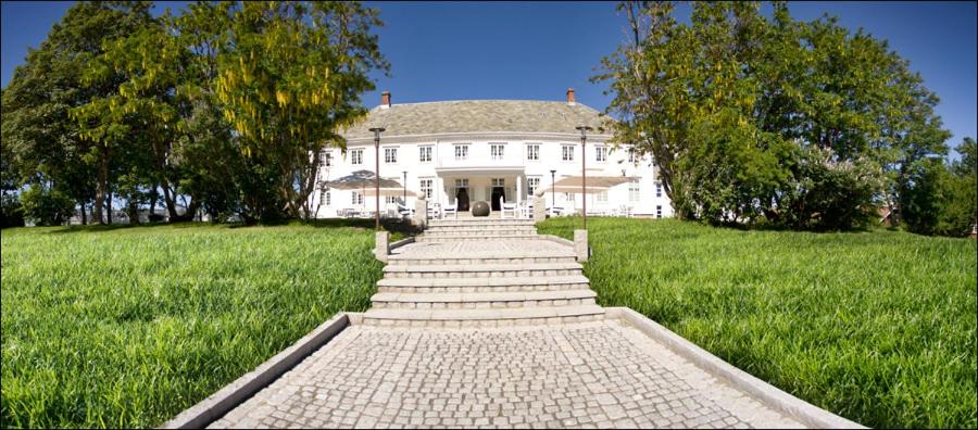 une grande maison blanche avec une passerelle dans un champ dans l'établissement Hovde Gård, à Brekstad