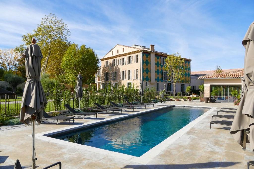 una piscina con sedie e ombrelloni accanto a un edificio di Bastide Saint Julien a La Celle