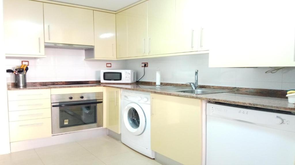 een keuken met witte kasten en een wasmachine en droger bij SHG APARTAMENTOS MONT-ROIG in Montroig