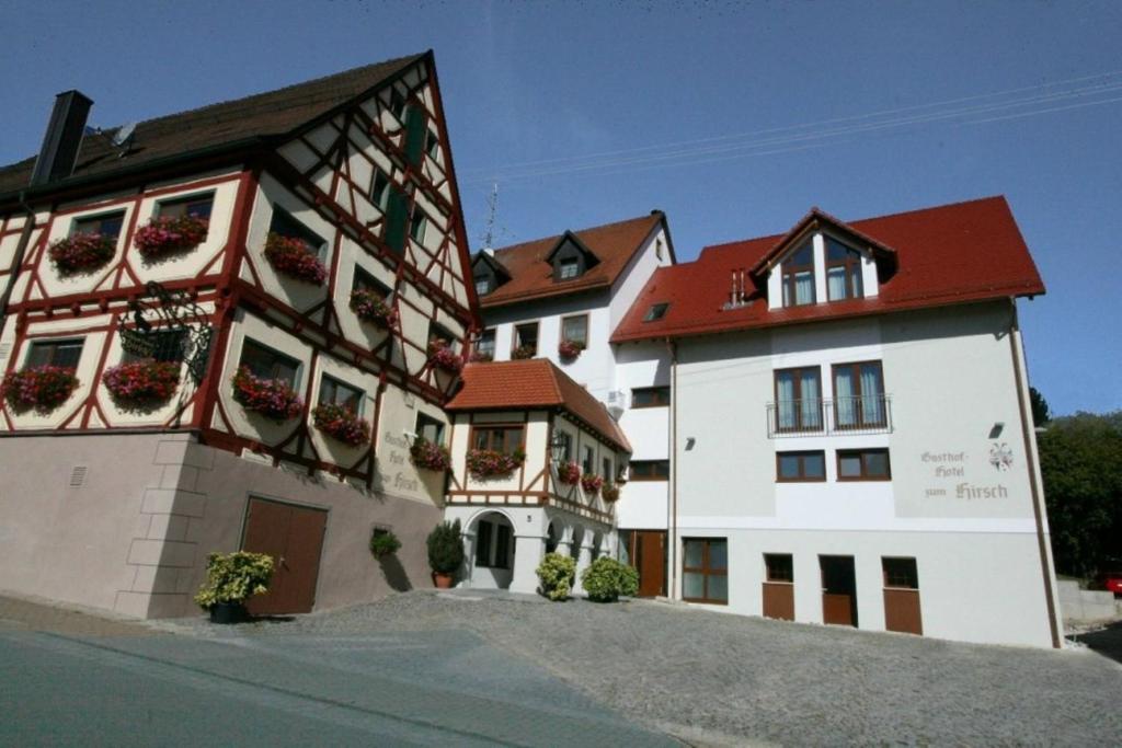 Gasthof Hotel Zum Hirsch***S في Kirchen: عمارتين عليها علب ورد