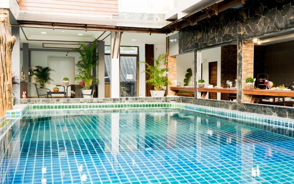 a swimming pool with blue tiles in a house at Billabong Hotel and Cafe in Baan Tai