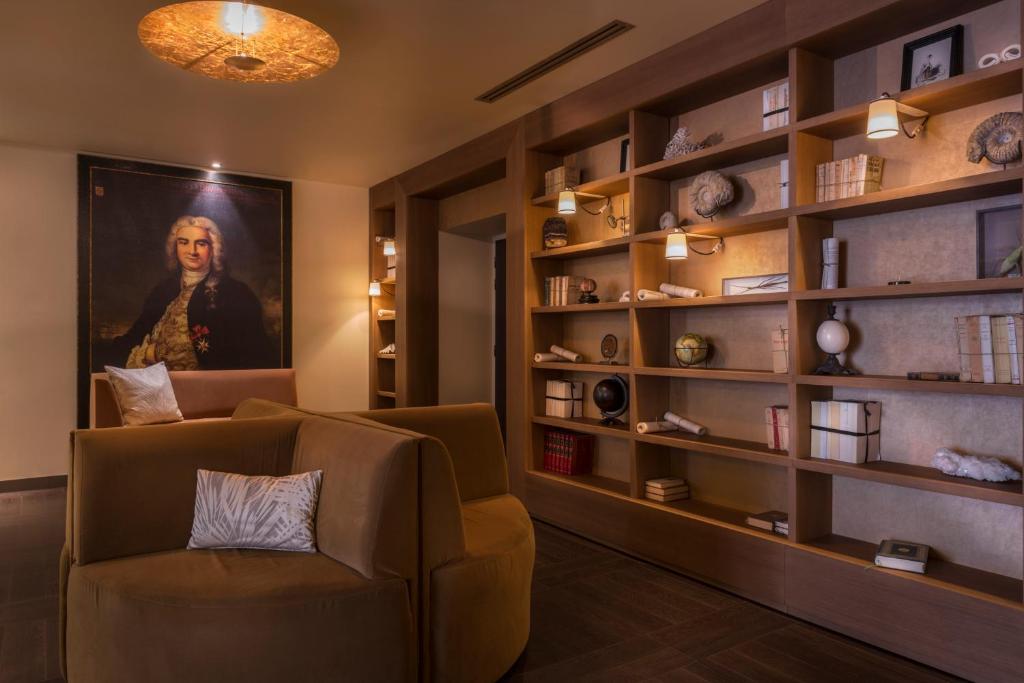 a living room with a chair and a large book shelf at Hôtel La Bourdonnais by Inwood Hotels in Paris