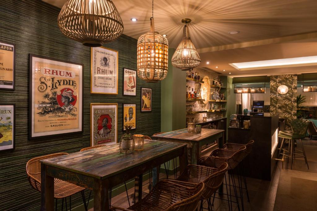 a restaurant with tables and chairs and posters on the walls at Hôtel La Bourdonnais by Inwood Hotels in Paris