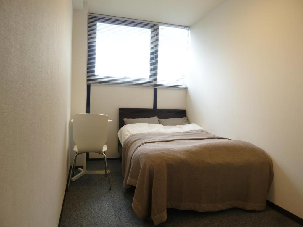 ein Schlafzimmer mit einem Bett, einem Fenster und einem Stuhl in der Unterkunft Nagoya Motoyama House C in Nagoya