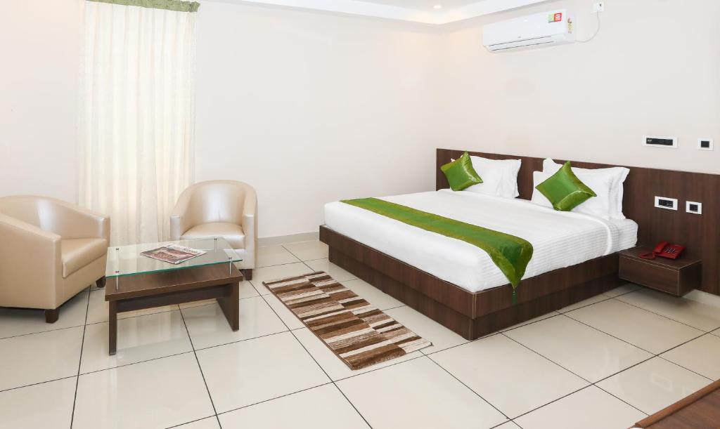 1 dormitorio con 1 cama, 1 silla y 1 mesa en Treebo Trend Durga Boji Grand Gonikoppal Town en Gonikoppal