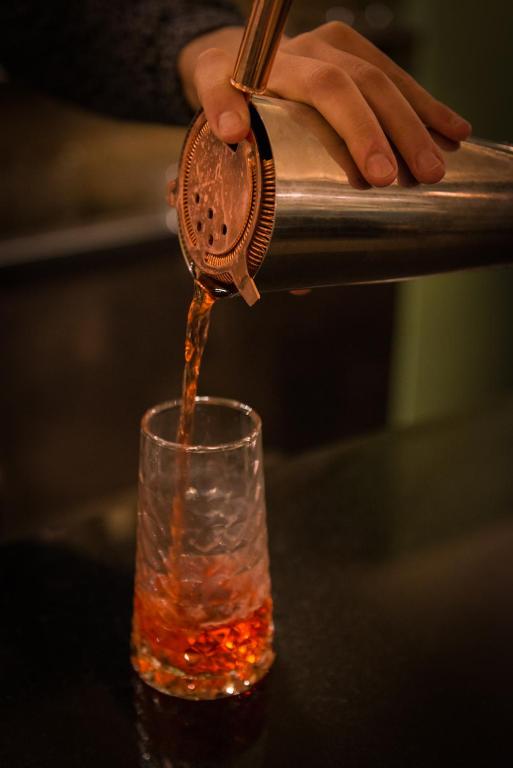 a person pouring a drink into a glass at Hôtel La Bourdonnais by Inwood Hotels in Paris
