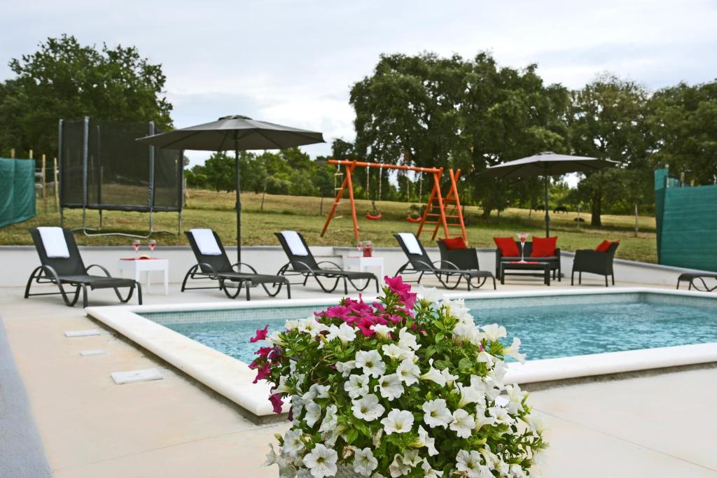 - une piscine avec des chaises, une balançoire et des fleurs dans l'établissement Villa Luna - beautiful, modern and luxurious, à Pula