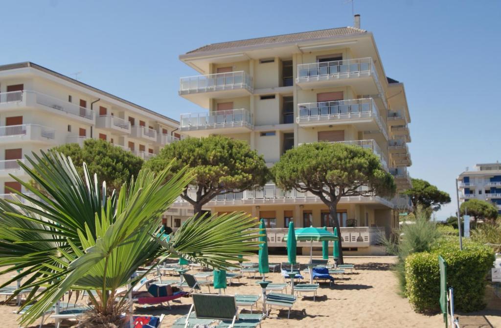 un hotel en la playa con sillas y árboles en Appartamenti Diplomatic-Residence Fronte mare-Piazza Torino-Lido di Jesolo, en Lido di Jesolo