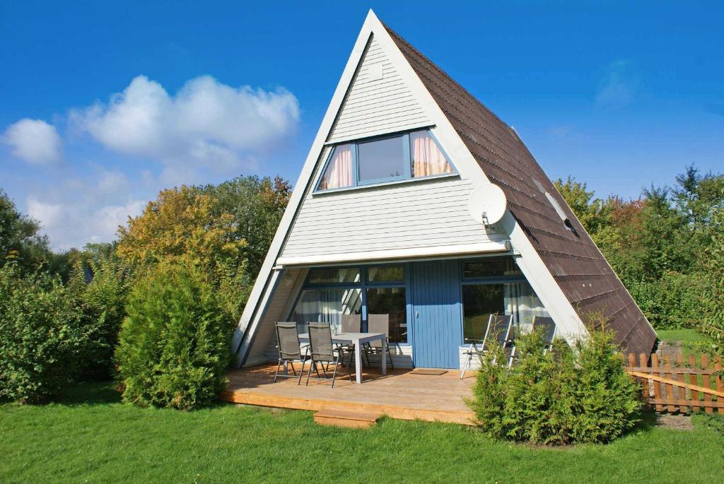 ein Haus mit einem dreieckigen Dach und einer Holzterrasse in der Unterkunft Zeltdachhaus mit WLan und Zaun in Damp