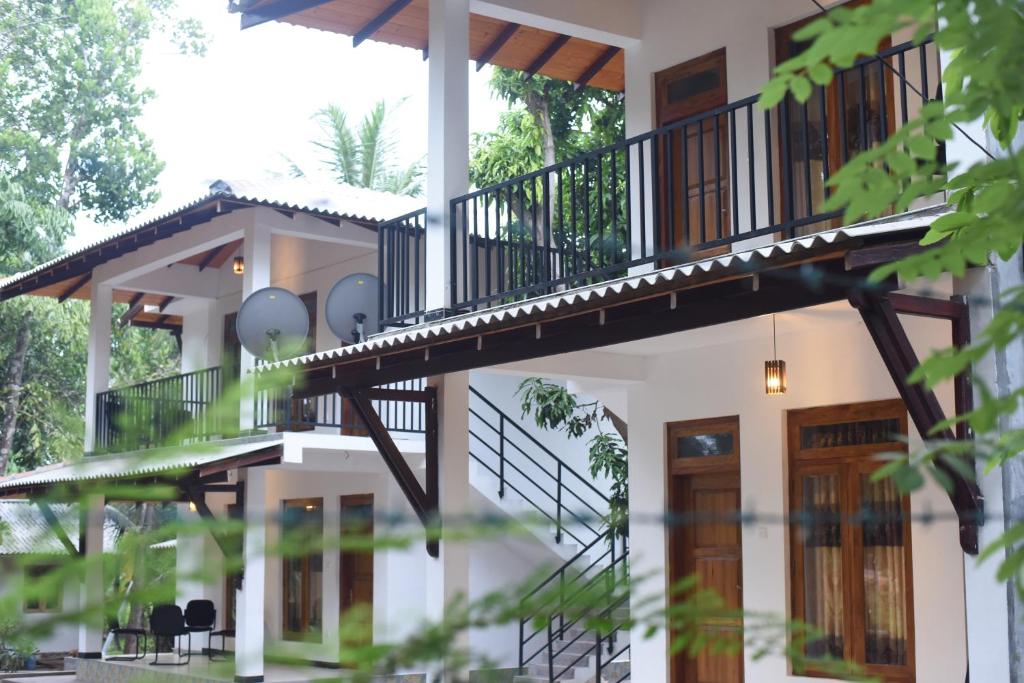 a house with a balcony and a staircase at Kithmi Resort in Polonnaruwa