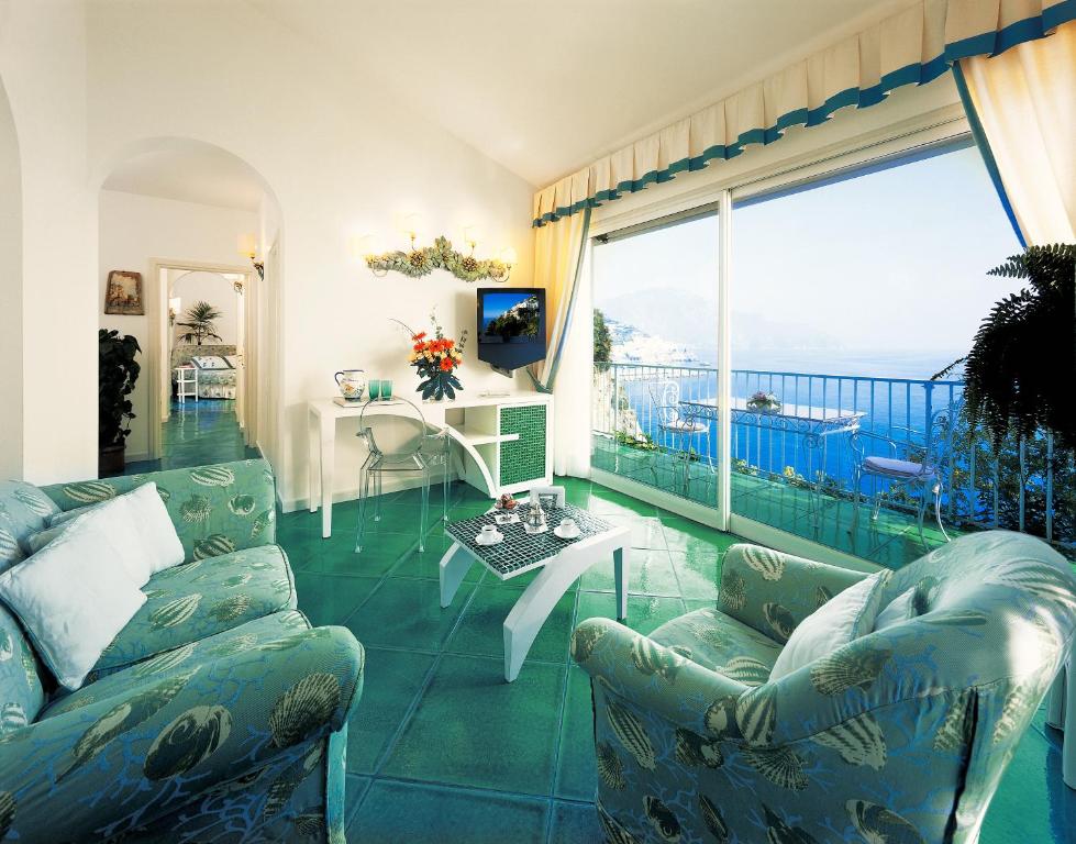 a living room with a couch and a table and a balcony at Hotel Santa Caterina in Amalfi