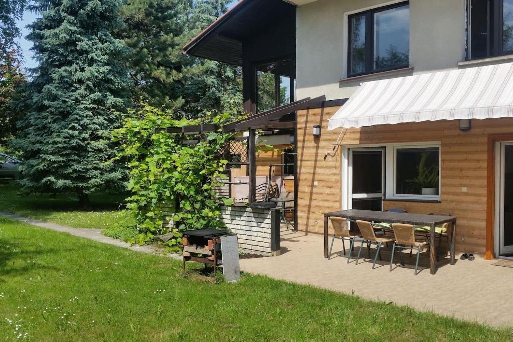 a patio with a table and chairs in front of a house at Świnna - Brzozowy Zagajnik in Świnna