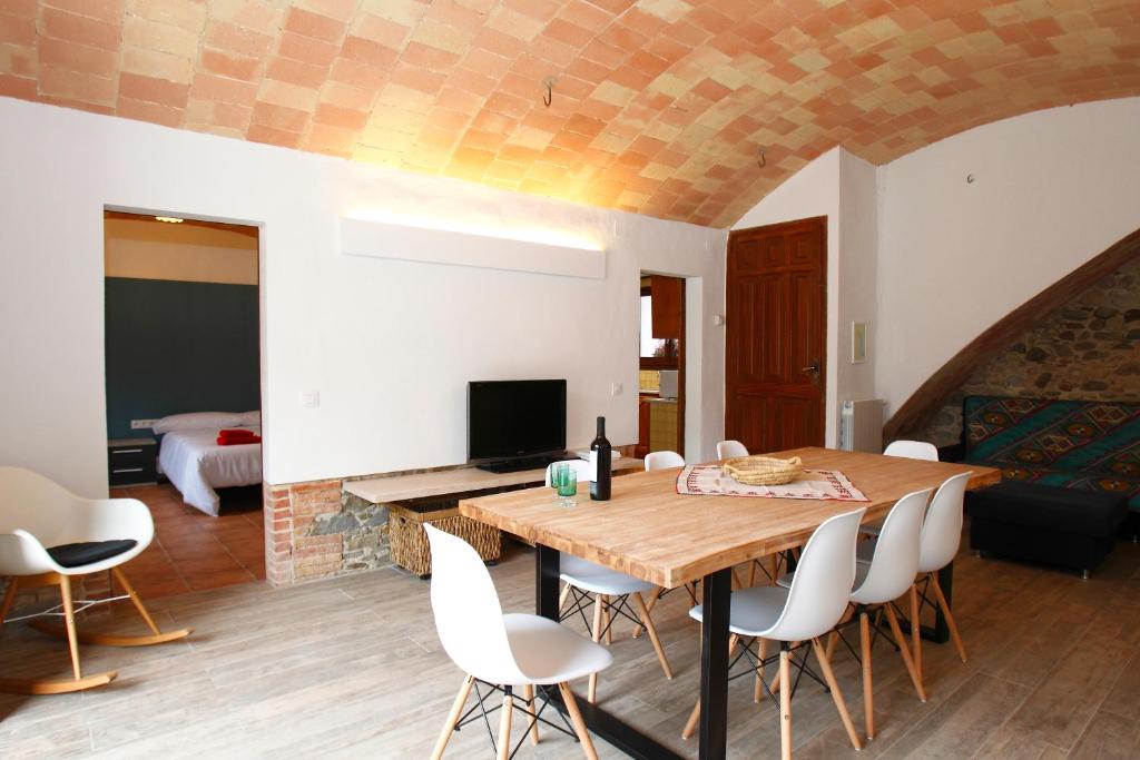una sala da pranzo con tavolo in legno e sedie bianche di Can Quel dels Alls - Best friendly a Celrá