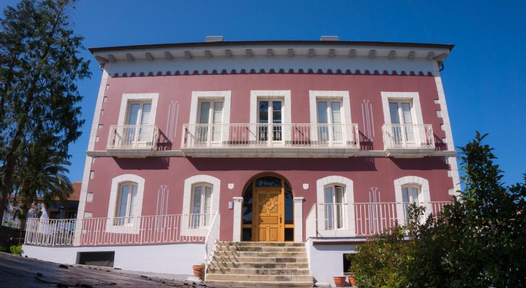 a pink building with a yellow door and stairs at Apartamentos Playas de Noja in Noja