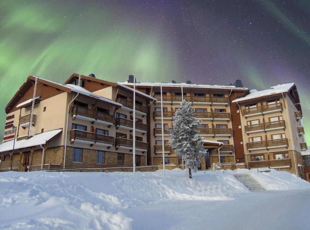 a hotel with the aurora in the sky in the snow at Santa's Hotel Tunturi in Saariselka
