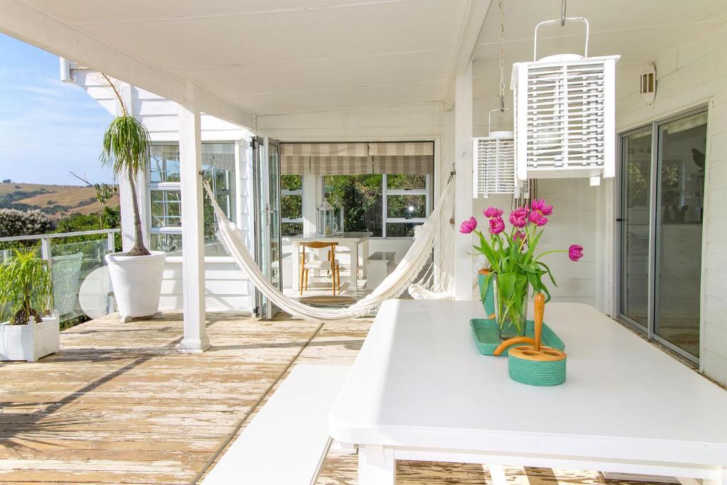 a porch with a white table and flowers on it at The Sullies in Morganʼs Bay