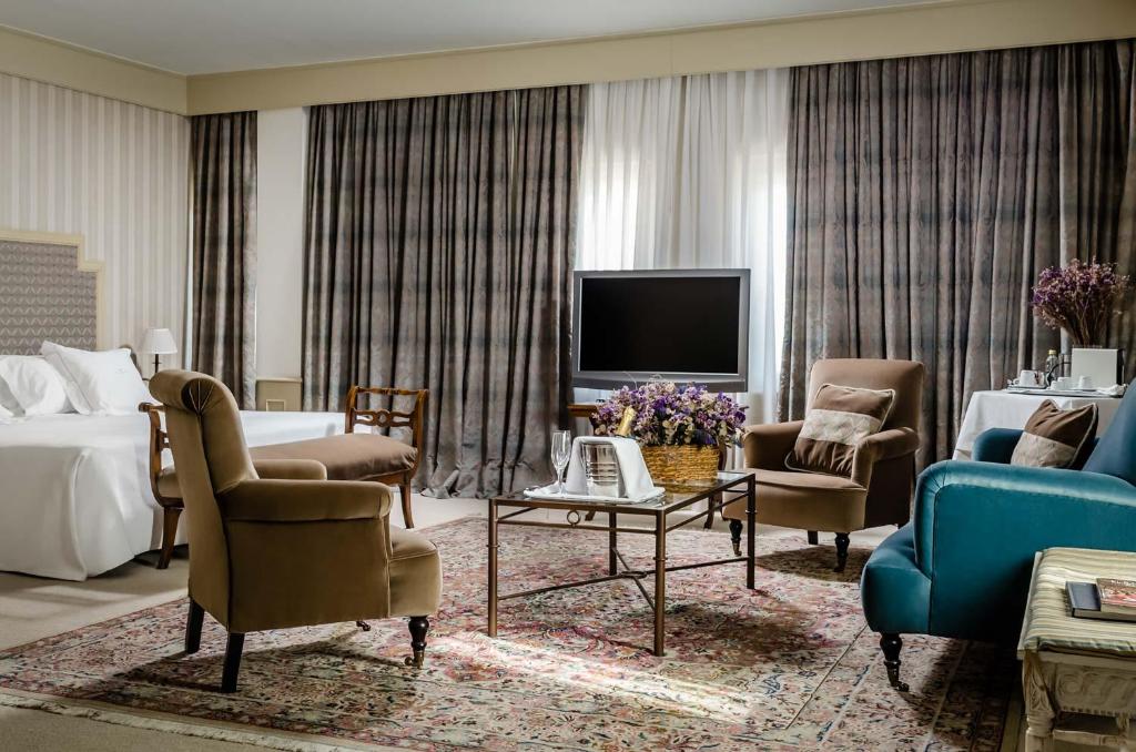 um quarto de hotel com uma cama e uma televisão e uma sala de estar em Gran Hotel La Perla em Pamplona