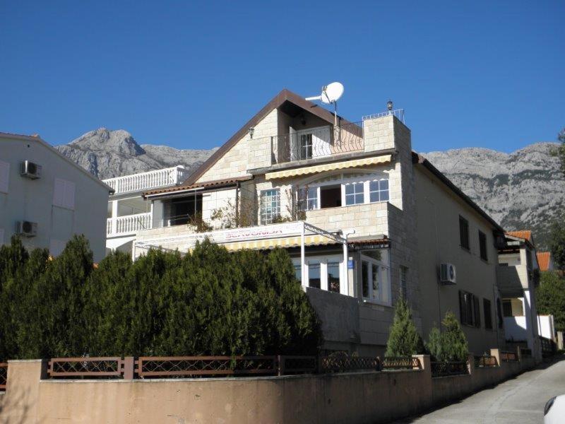 ein Haus auf einer Straße mit Bergen im Hintergrund in der Unterkunft Apartmani Slavonija in Orebić