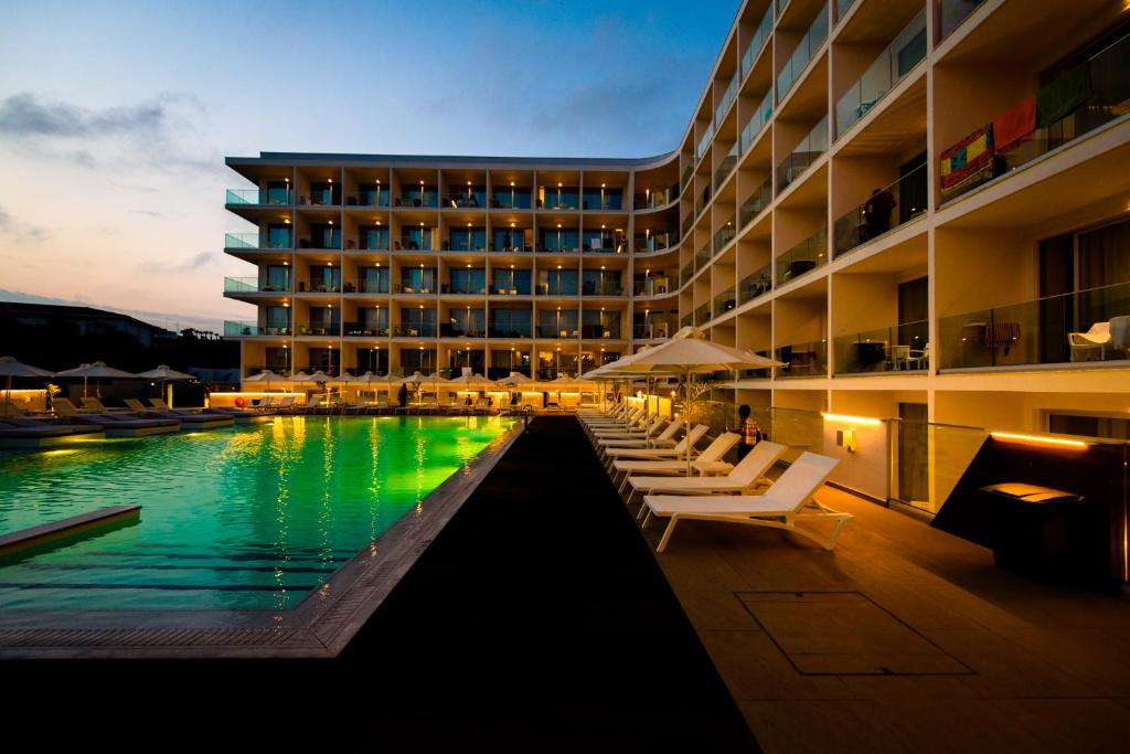 a hotel with a pool and lounge chairs in front of a building at Eleana Hotel in Ayia Napa