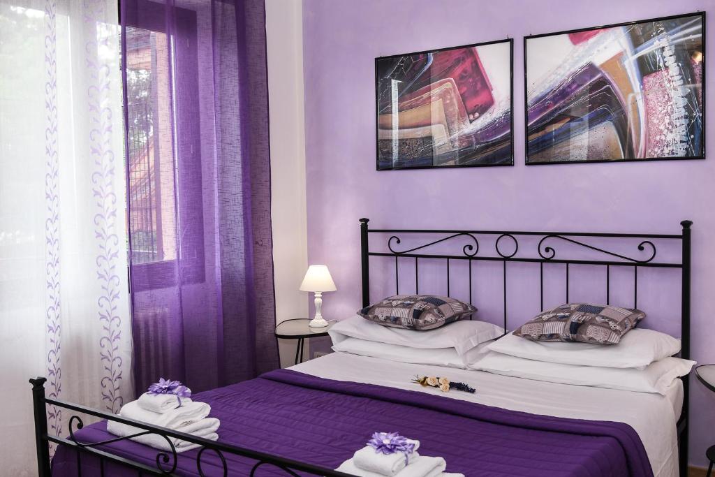 - une chambre violette avec un lit doté de draps et d'oreillers violets dans l'établissement B&B Villa Sophie, à Assise