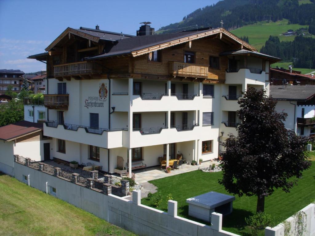 un grand bâtiment blanc avec un toit en bois dans l'établissement Pension Lärchenbrunn, à Westendorf