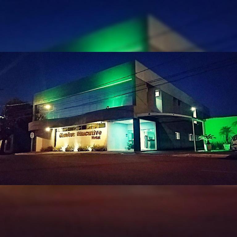 a building with green lights on the side of it at Nantes Executive Hotel in Pitanga