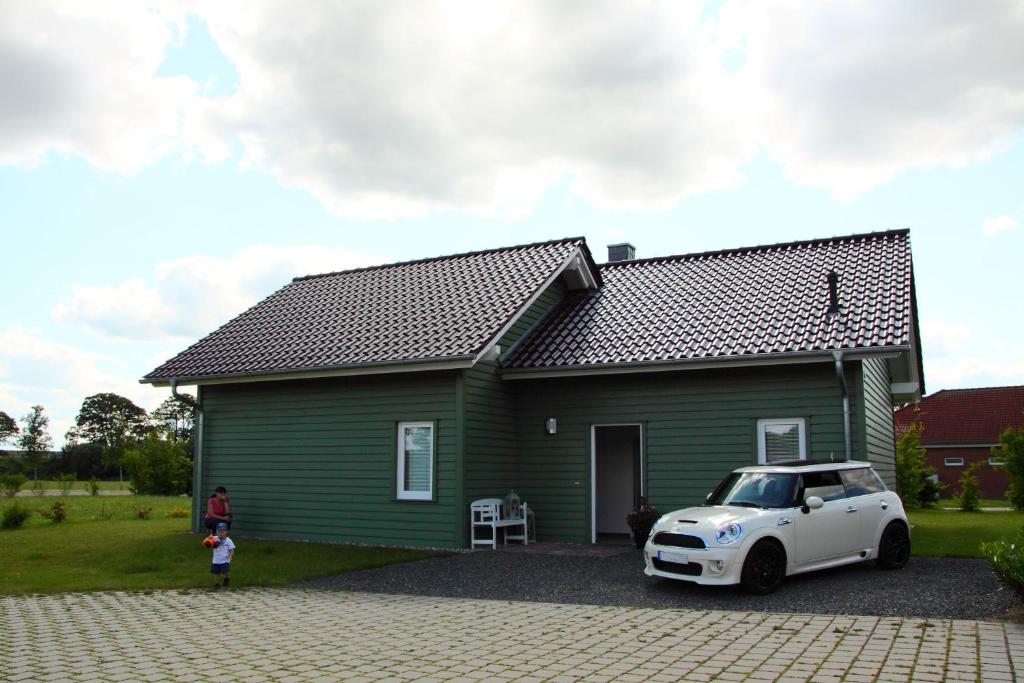 uma pequena casa verde com um carro branco estacionado em frente em Ferienhaus am Schaalsee em Zarrentin