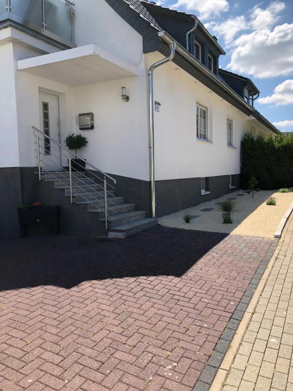 a white building with a staircase next to a brick driveway at Ferienwohnung mit Balkon in Calden in Calden