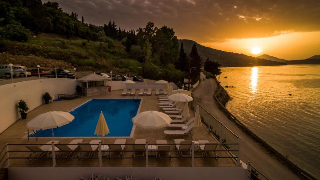 a pool with chairs and umbrellas next to a body of water at Golden Sunset in Boukari