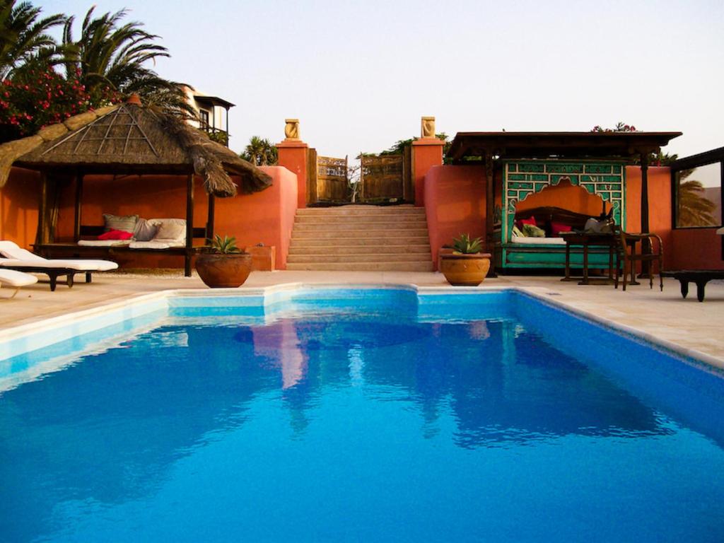 a blue swimming pool next to a house with a gazebo at Casa El Morro in Uga