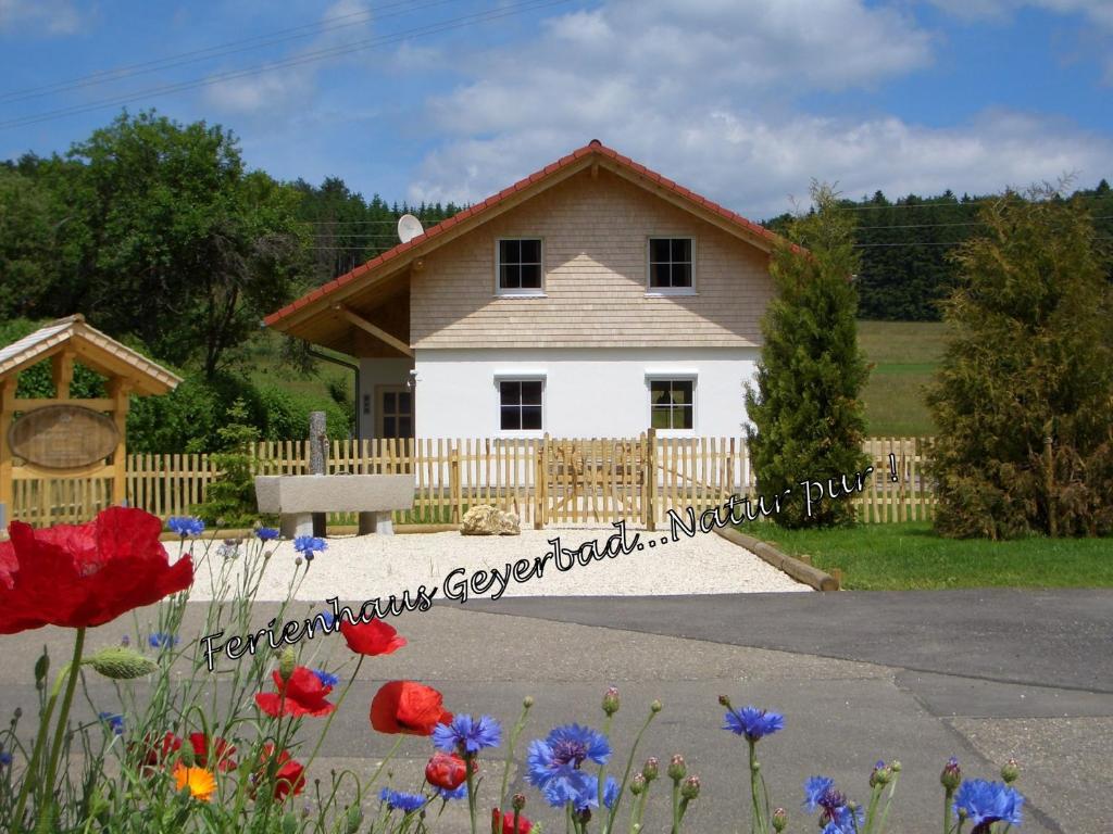 ein Haus mit einem Zaun und Blumen davor in der Unterkunft Ferienhaus Geyerbad in Meßstetten