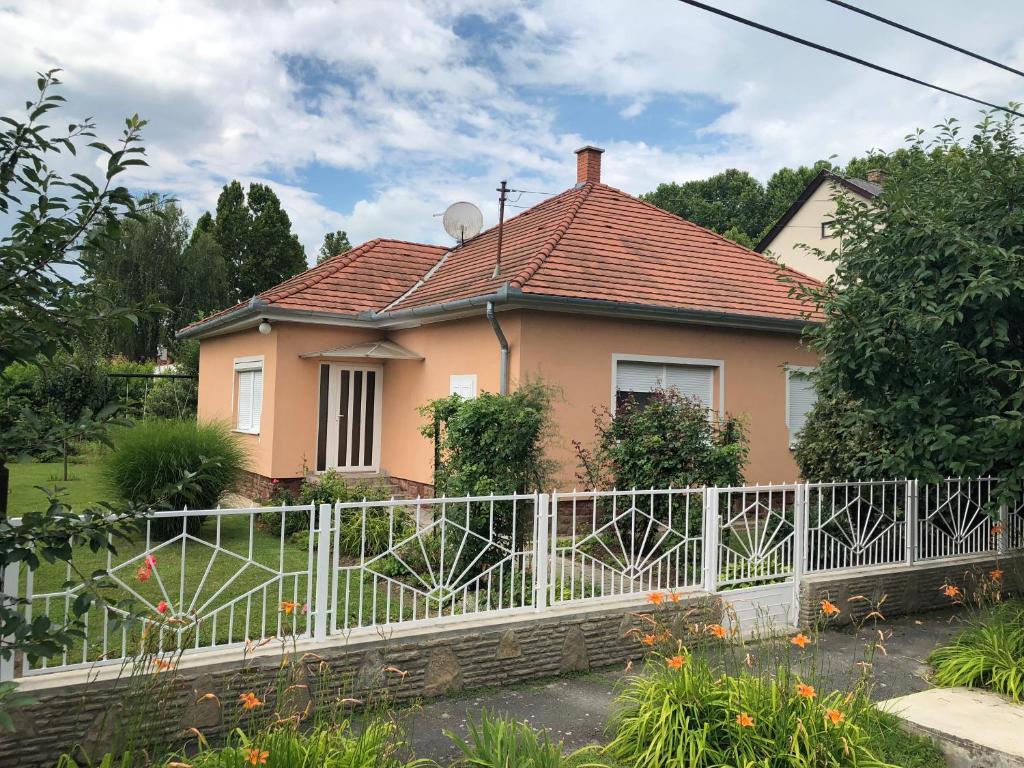 une maison rose avec une clôture blanche dans l'établissement Liget nyaralóház, à Balatonföldvár