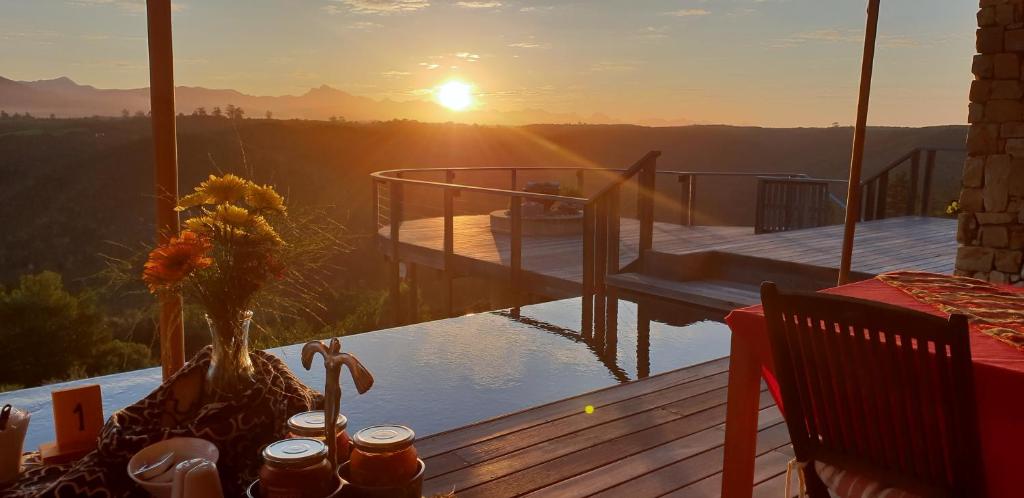 puesta de sol en una terraza con vistas a las montañas en Tamodi Lodge, en Plettenberg Bay