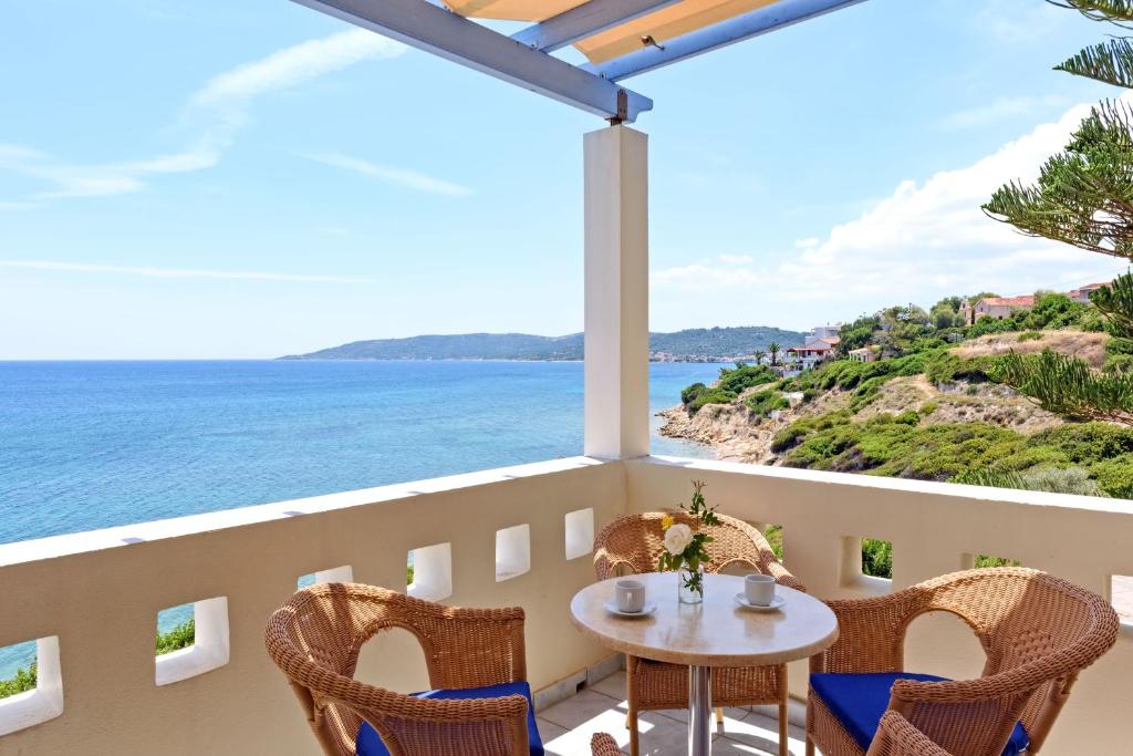 uma varanda com uma mesa e cadeiras e o oceano em Sea Breeze Apartments Chios em Monolia