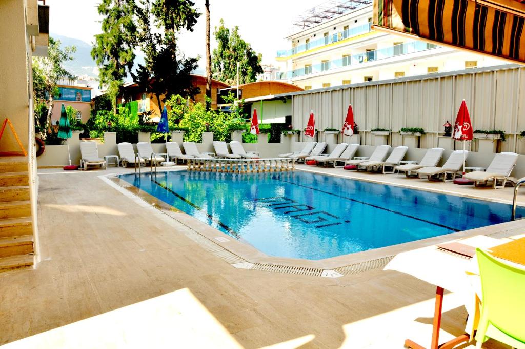 a swimming pool with lounge chairs and a hotel at Magi Apart Hotel in Alanya