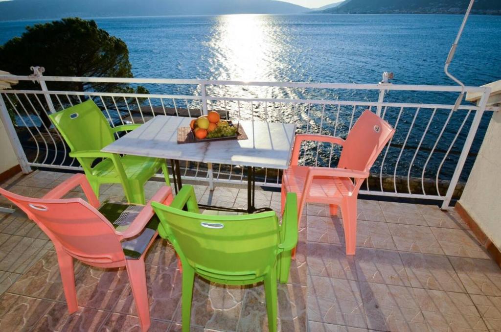 einen Tisch und Stühle auf einem Balkon mit Meerblick in der Unterkunft Apartments Olga in Tivat