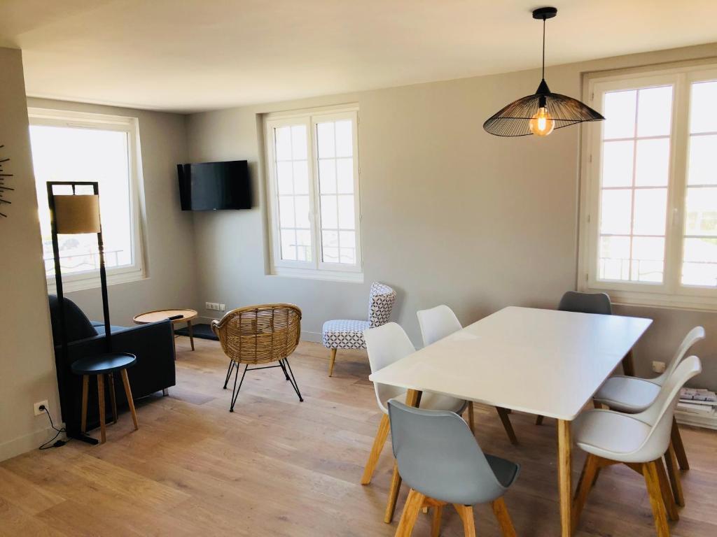 une salle à manger avec une table et des chaises blanches dans l'établissement Bel Appartement vue mer, à Merville-Franceville-Plage