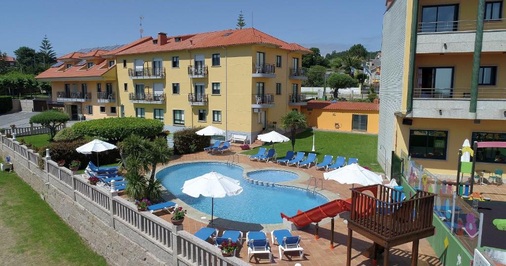 a swimming pool with chairs and umbrellas next to a building at Hotel Atlántico Sanxenxo in Montalvo