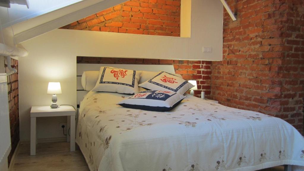 a bedroom with a bed and a brick wall at New York Laisvės al 51A in Kaunas