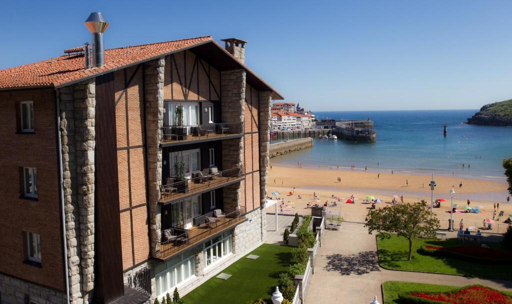 ein Gebäude neben einem Strand mit Leuten darauf in der Unterkunft Hotel Silken Palacio Uribarren in Lekeitio