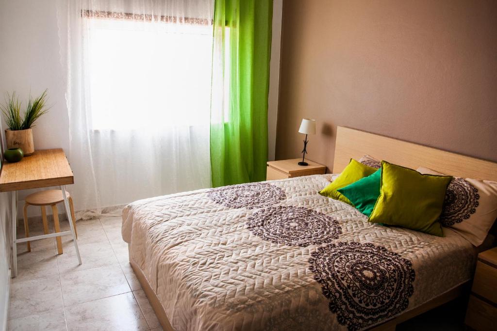 ラゴスにあるCasa Polaのベッドルーム1室(緑のカーテンと窓付きのベッド1台付)