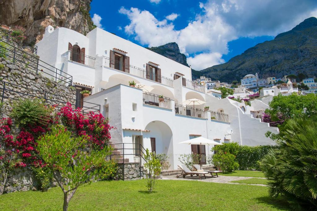 a white building with flowers on the side of a mountain at villa virginia in Positano