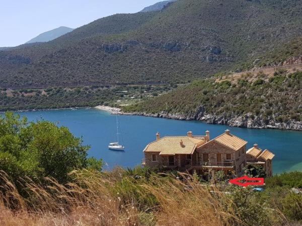a house on a lake with a boat in the water at Two-storey Mansion at the Sea in Arkadiko Chorio