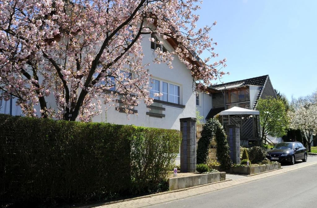 une maison avec un arbre à fleurs en face d'une rue dans l'établissement Pension Bella Vista, à Bochum
