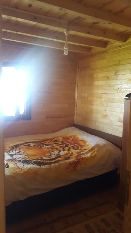 una cama en una habitación con una pared de madera en Yeşilyurt dağ tesisi, en Yeniköy