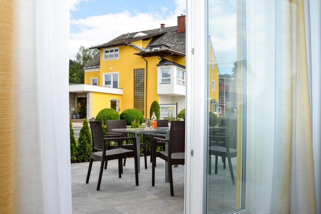 a patio with a table and chairs and a yellow house at KM Hotel Murtal in Knittelfeld