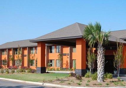 a building with a palm tree in front of it at LikeHome Extended Stay Hotel Warner Robins in Warner Robins