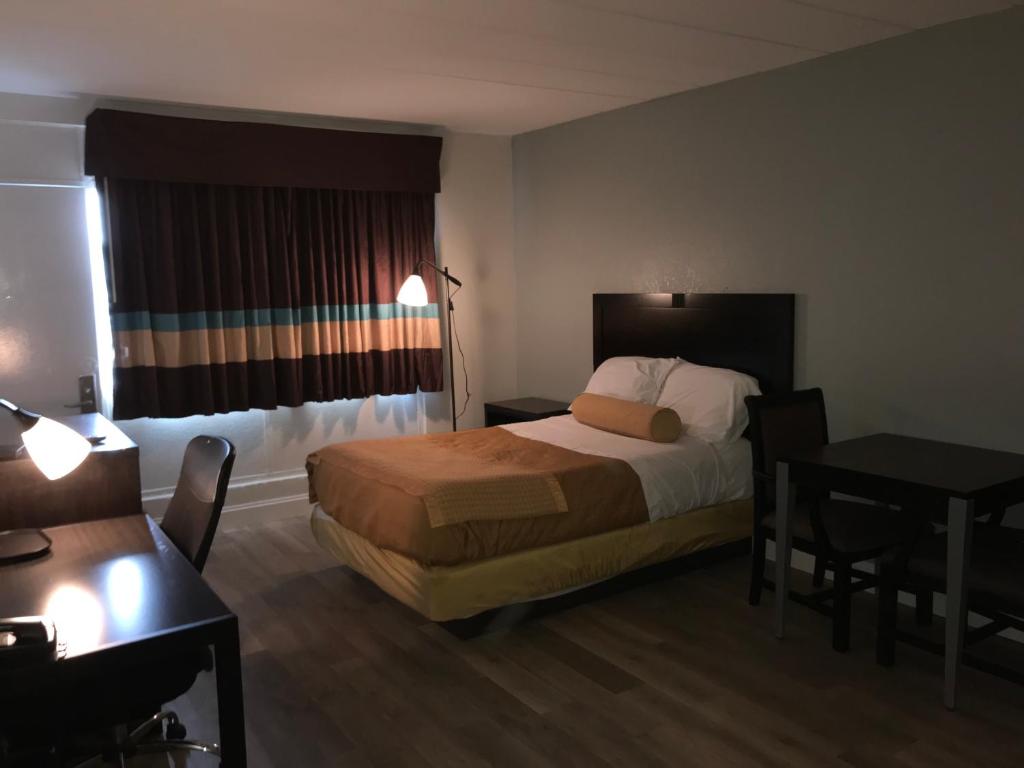 Habitación de hotel con cama y escritorio en Belmont Inn & Suites Virginia Beach, en Virginia Beach