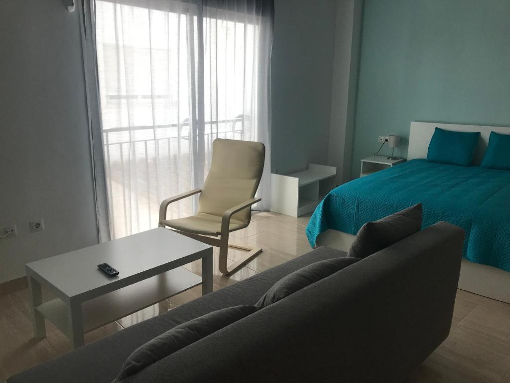 ein Wohnzimmer mit einem Bett, einem Sofa und einem Stuhl in der Unterkunft Calle Ollerias in Málaga