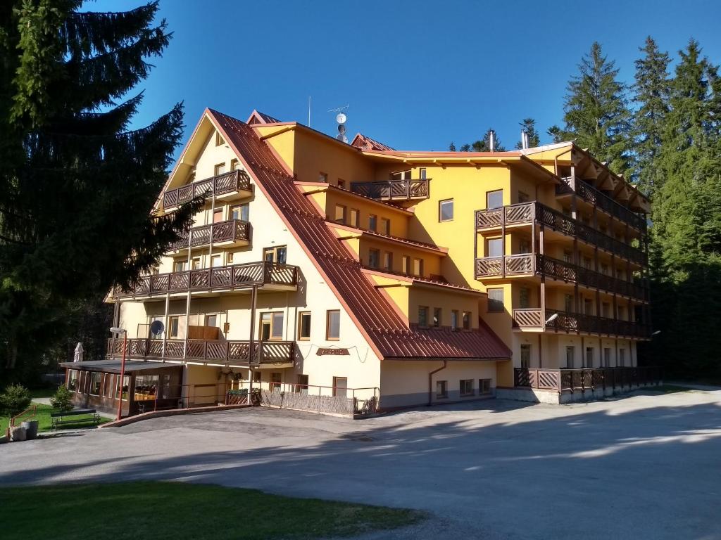 ein großes gelbes Gebäude mit Balkonen darauf in der Unterkunft Apartmány Mirka a Maťko in Donovaly